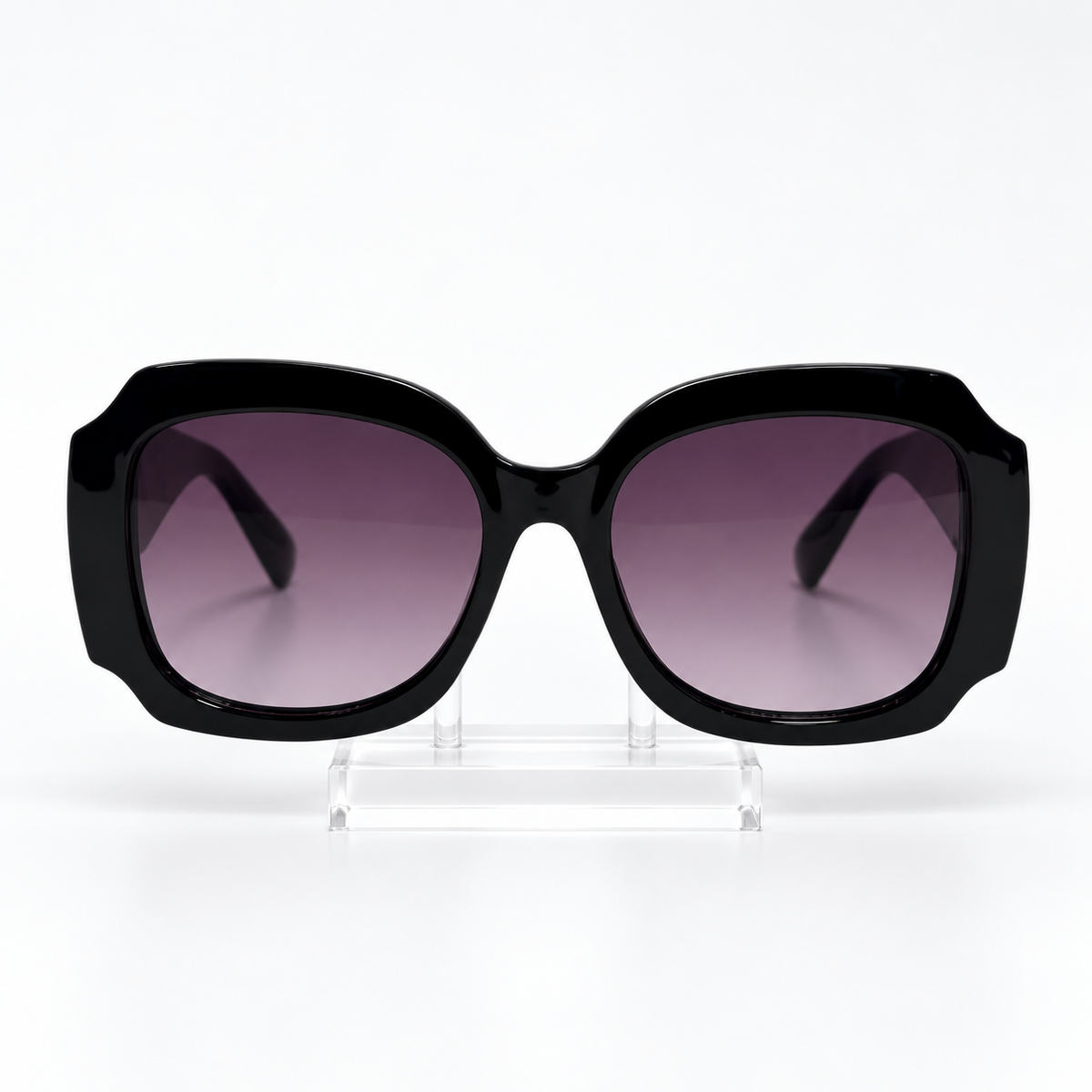 Oversized square sunglasses with a glossy black frame and gradient purple-tinted lenses, displayed on a clear acrylic stand against a white background.