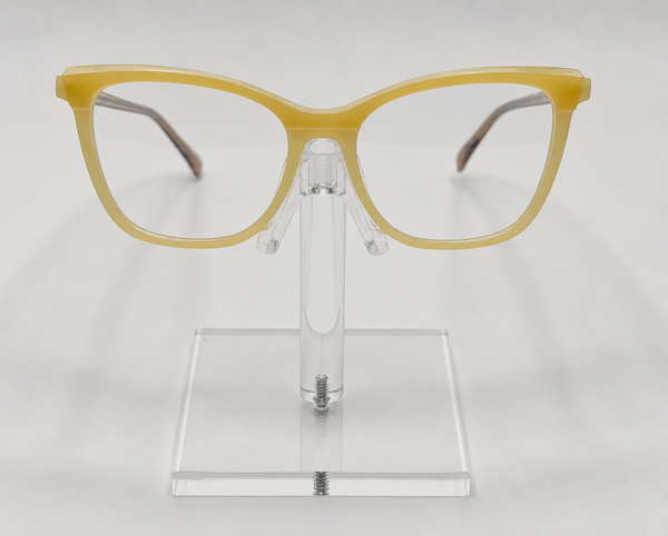Yellow cat-eye eyeglasses displayed on a clear acrylic stand against a light gray background.