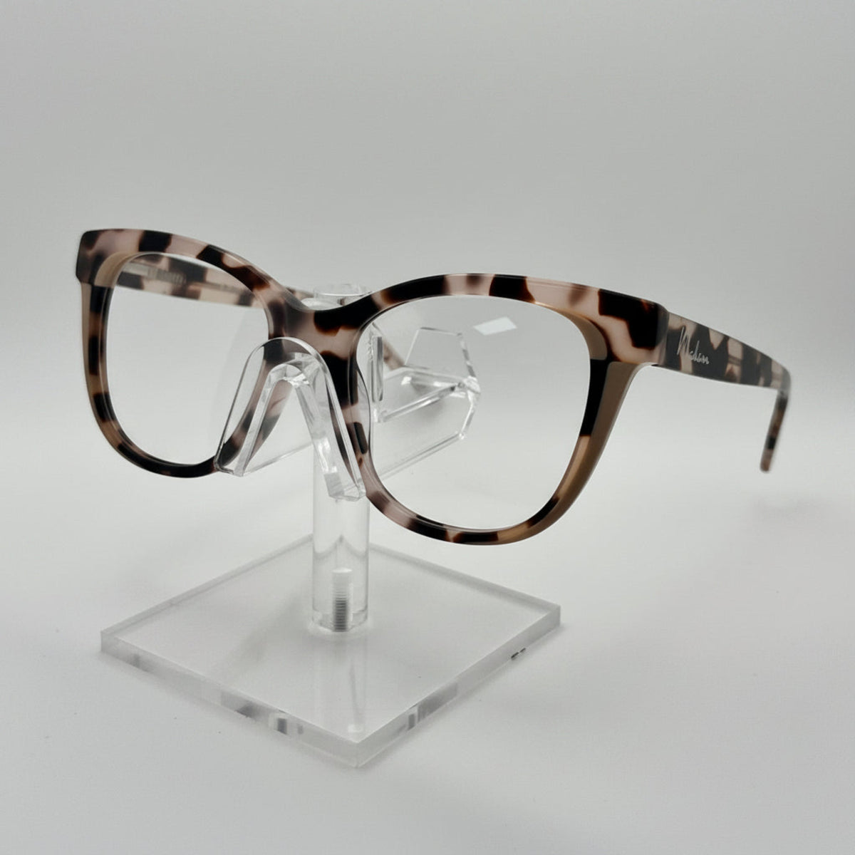 Eyeglasses with tortoiseshell frame on a clear stand against a white background