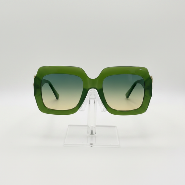 Green oversized square sunglasses with gradient lenses, displayed on a clear acrylic stand against a white background.