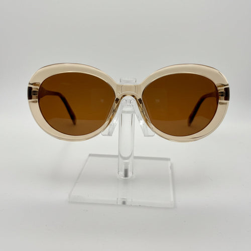 Sunglasses with gold frame and brown lenses on a clear stand against a white background