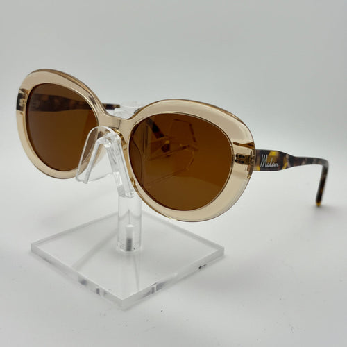 Gold-framed sunglasses with brown lenses on a clear stand against a white background