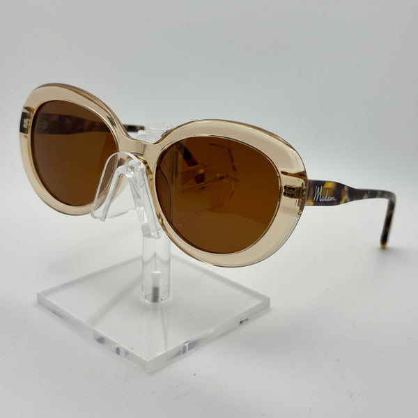 Gold-framed sunglasses with brown lenses on a clear stand against a white background