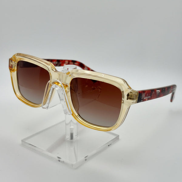 Gold-framed sunglasses on a clear stand against a gray background