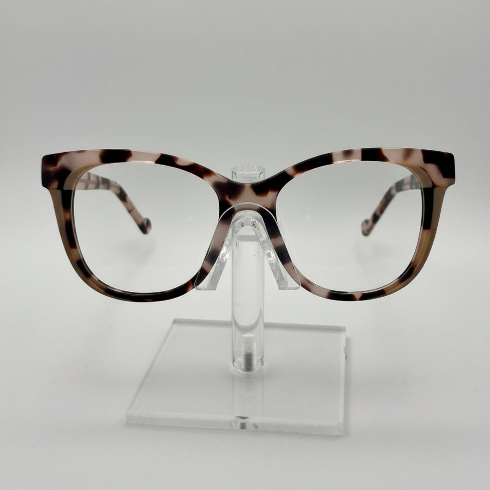Tortoiseshell eyeglasses on a clear stand against a white background