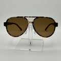 A pair of oversized aviator-style sunglasses with a tortoiseshell patterned frame and brown tinted lenses, displayed on a clear acrylic stand against a white background.