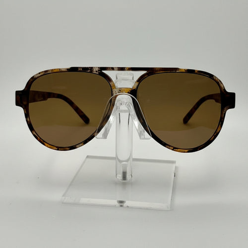 A pair of oversized aviator-style sunglasses with a tortoiseshell patterned frame and brown tinted lenses, displayed on a clear acrylic stand against a white background.