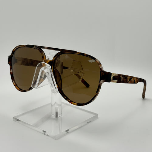 Aviator-style sunglasses with oversized brown-tinted lenses and a tortoiseshell patterned frame, displayed on a clear acrylic stand against a light gray background.