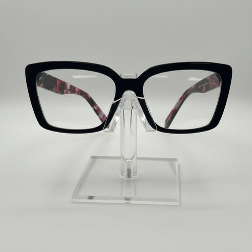 Black cat-eye eyeglasses with clear lenses and patterned inner temples, displayed on a clear acrylic stand against a white background.