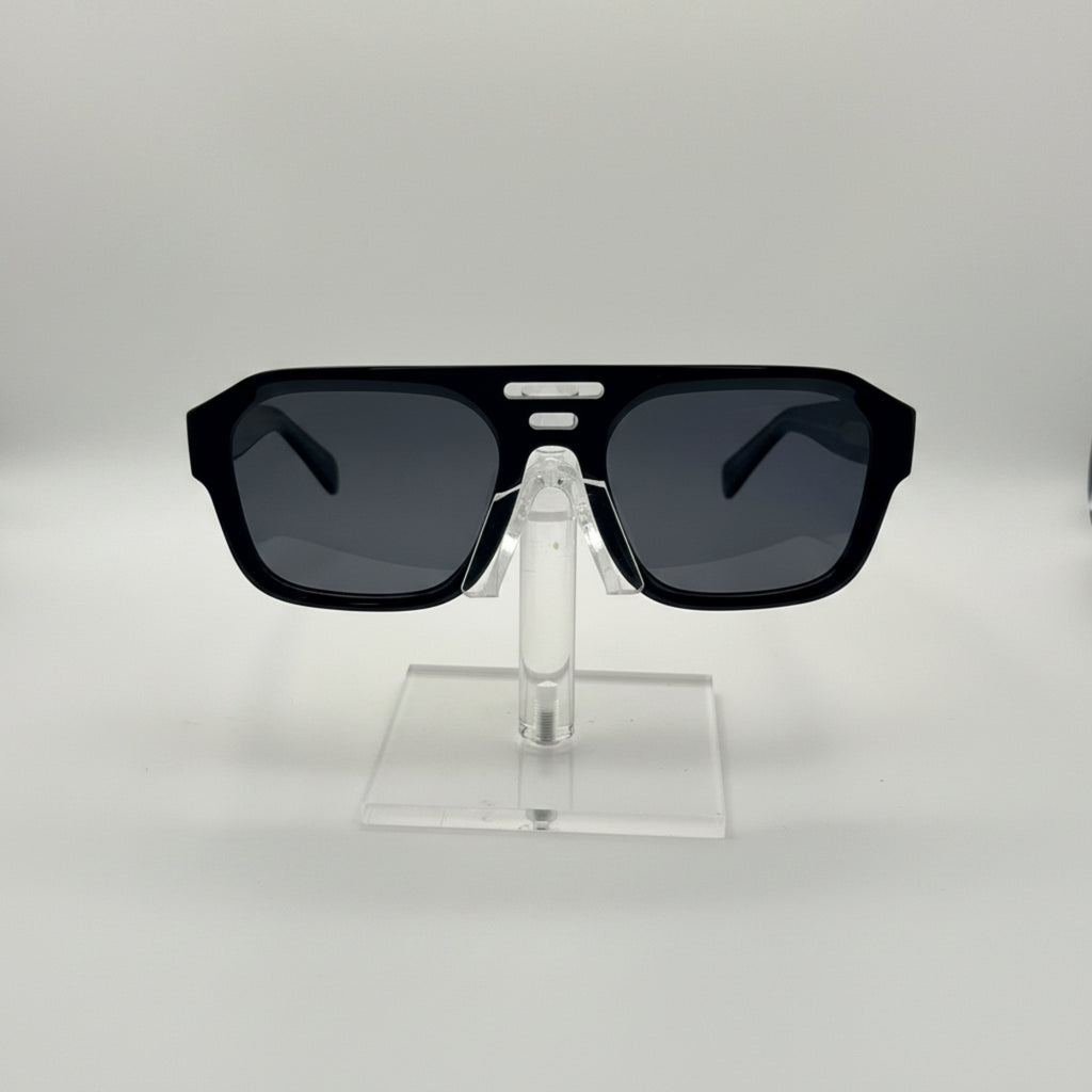 Black square sunglasses with dark lenses displayed on a clear acrylic stand against a light gray background.