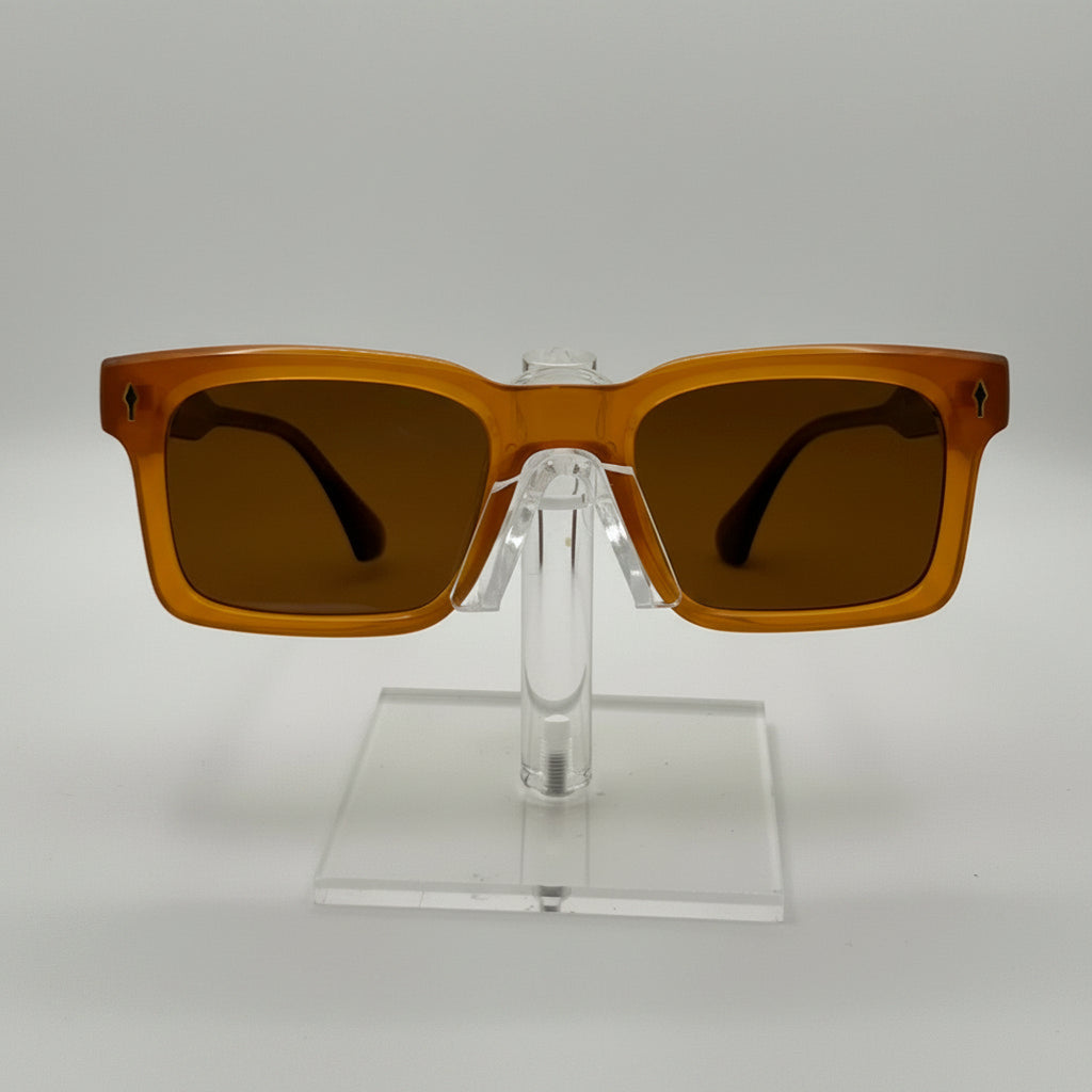 Rectangular sunglasses with translucent amber-brown frames and dark brown lenses, displayed on a clear acrylic stand against a light gray background.