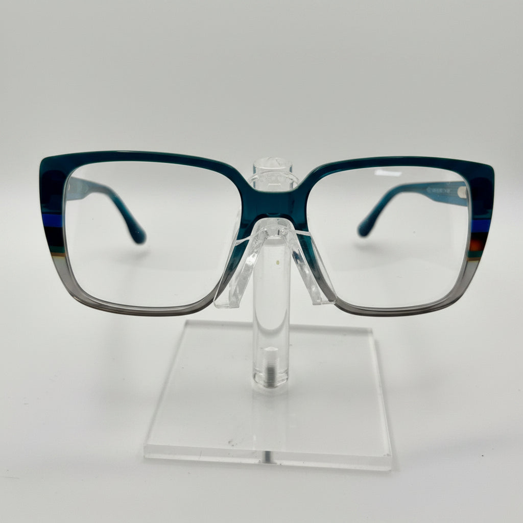 Rectangular eyeglasses with a translucent dark blue acetate frame and clear lenses, displayed on a clear acrylic stand against a white background.