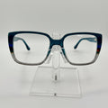 Rectangular eyeglasses with a translucent dark blue acetate frame and clear lenses, displayed on a clear acrylic stand against a white background.