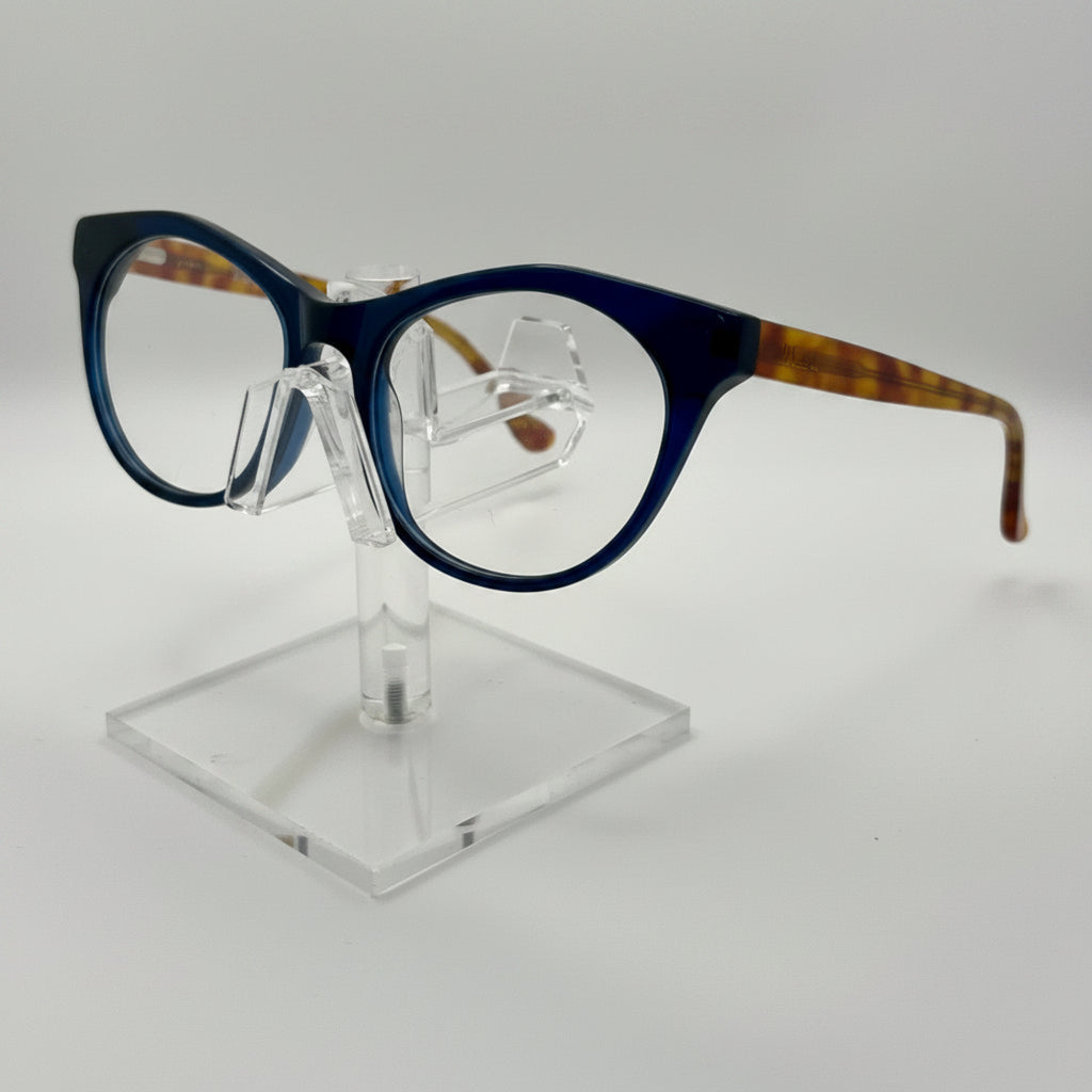 round eyeglasses with a dark blue front frame and tortoiseshell-patterned temples, displayed on a clear acrylic stand against a light gray background.
