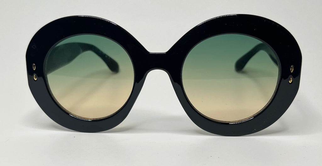 Oversized round sunglasses with a thick black frame and gradient lenses that fade from green at the top to beige at the bottom, shown against a plain white background.