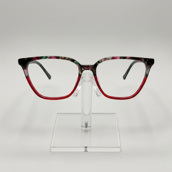 Fashionable square eyeglasses with a red acetate lower frame and a black, green, and pink marbled top frame, displayed on a clear stand against a light gray background.