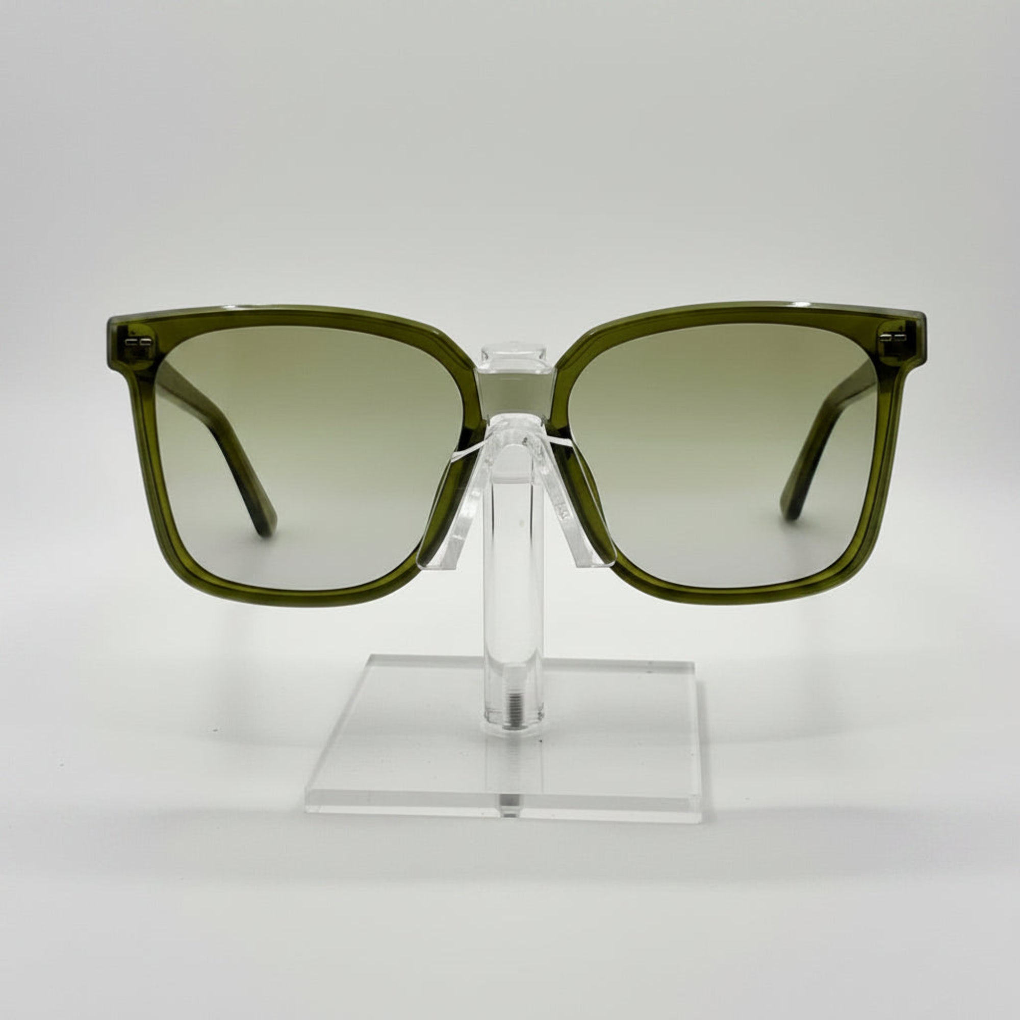 Green sunglasses on a clear stand against a white background