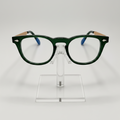 Dark green acetate eyeglass frames with light wood-look temples and blue temple tips, displayed on a clear acrylic stand against a light gray background.