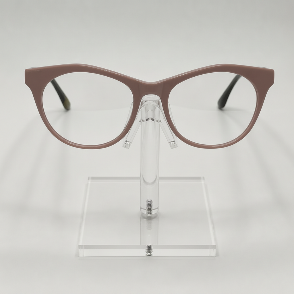 A pair of cat-eye eyeglasses with a matte taupe-brown frame, displayed on a clear acrylic stand against a light gray background.