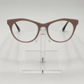 A pair of cat-eye eyeglasses with a matte taupe-brown frame, displayed on a clear acrylic stand against a light gray background.