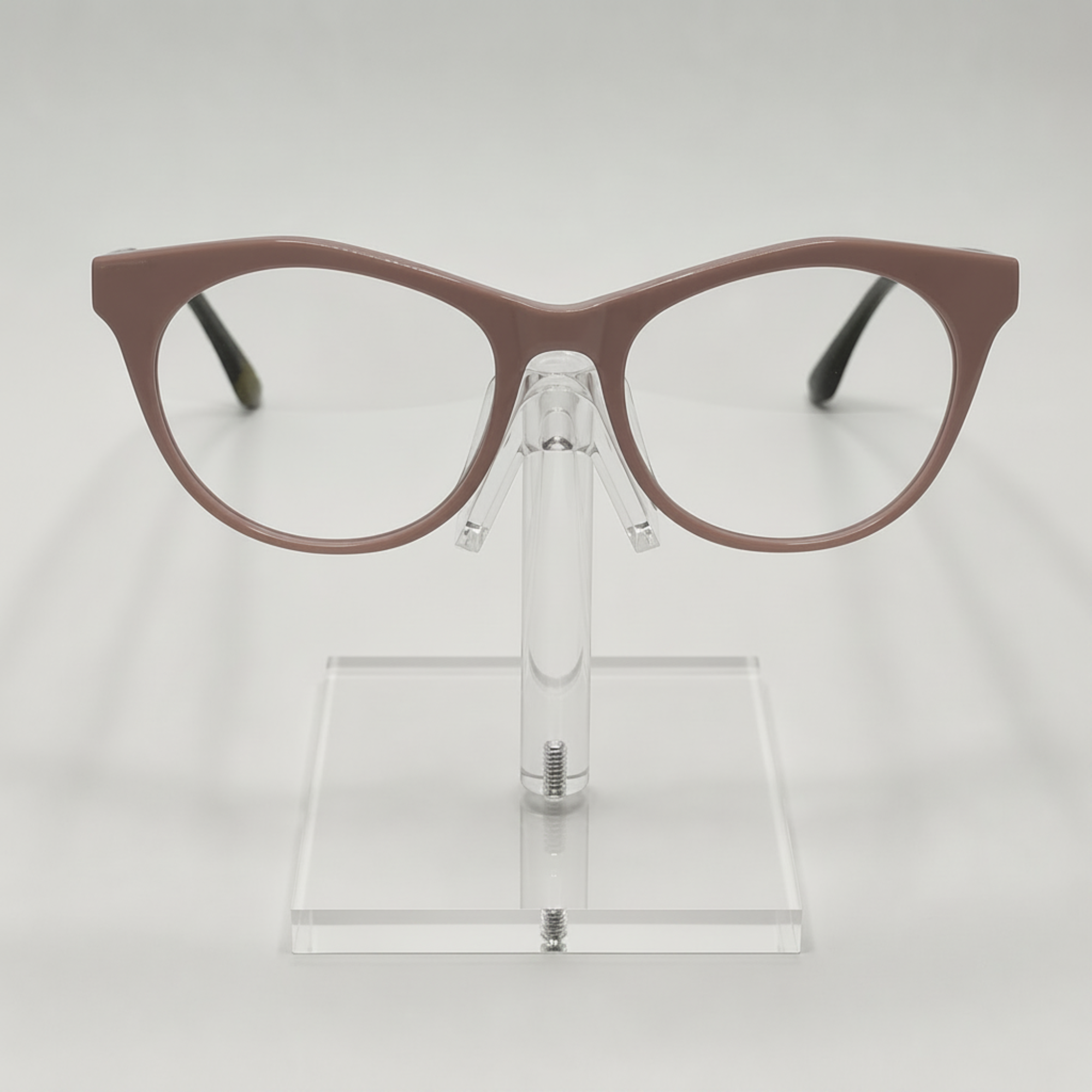 A pair of cat-eye eyeglasses with a matte taupe-brown frame, displayed on a clear acrylic stand against a light gray background.
