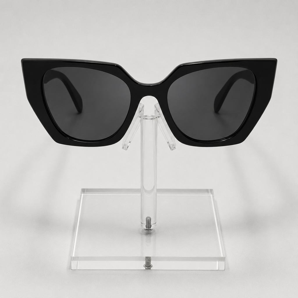 Black cat-eye sunglasses with dark lenses displayed on a clear acrylic stand against a light gray background.