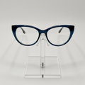 Crazy cat-eye eyeglasses with a dark blue acetate frame, displayed on a clear acrylic stand against a light gray background.