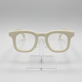Cream-colored thick-rimmed eyeglasses displayed on a clear acrylic stand against a light gray background.