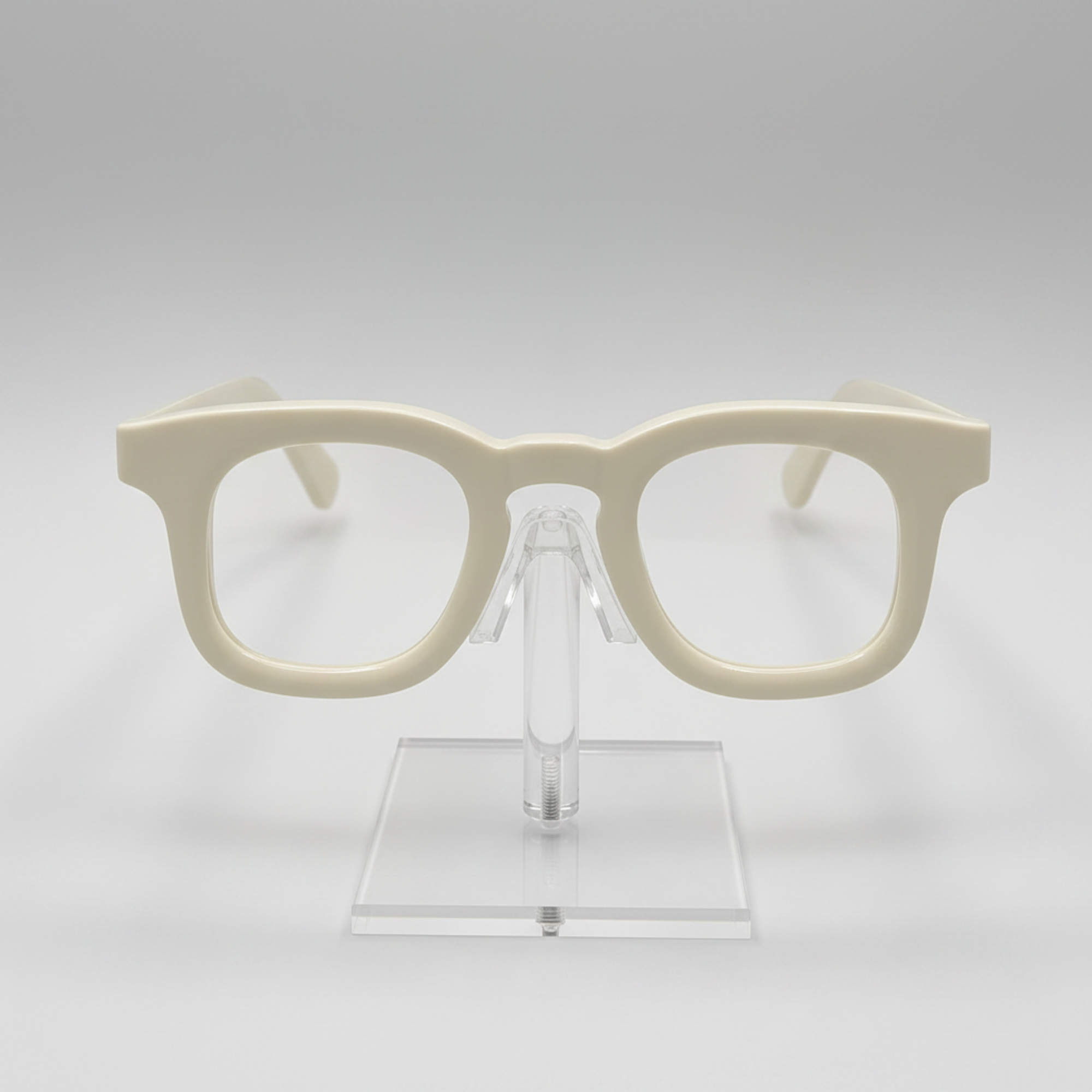 Cream-colored thick-rimmed eyeglasses displayed on a clear acrylic stand against a light gray background.