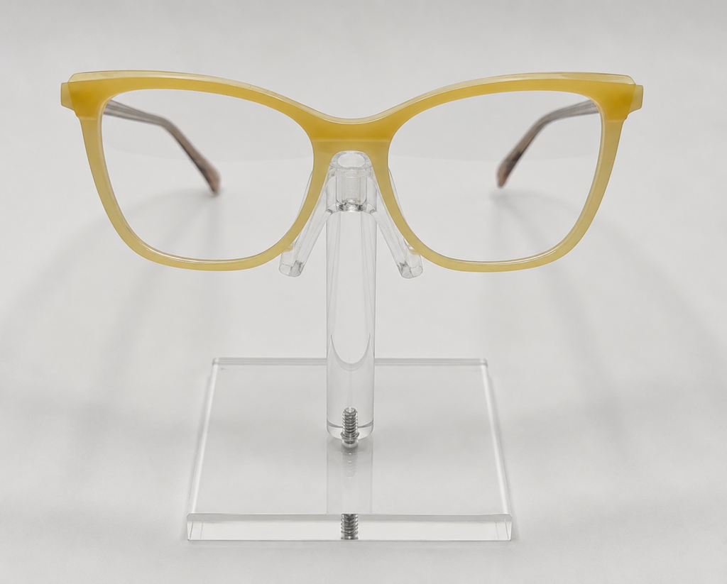 Yellow cat-eye eyeglasses displayed on a clear acrylic stand against a light gray background.