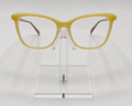 Yellow cat-eye eyeglasses displayed on a clear acrylic stand against a light gray background.