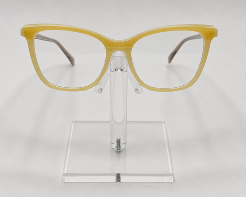Yellow cat-eye eyeglasses displayed on a clear acrylic stand against a light gray background.